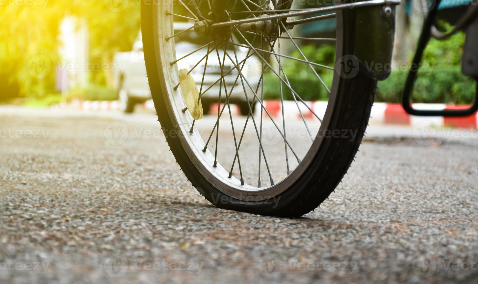 Closeup flat rear wheel of the bike which parked on pavement, soft and selective focus. photo