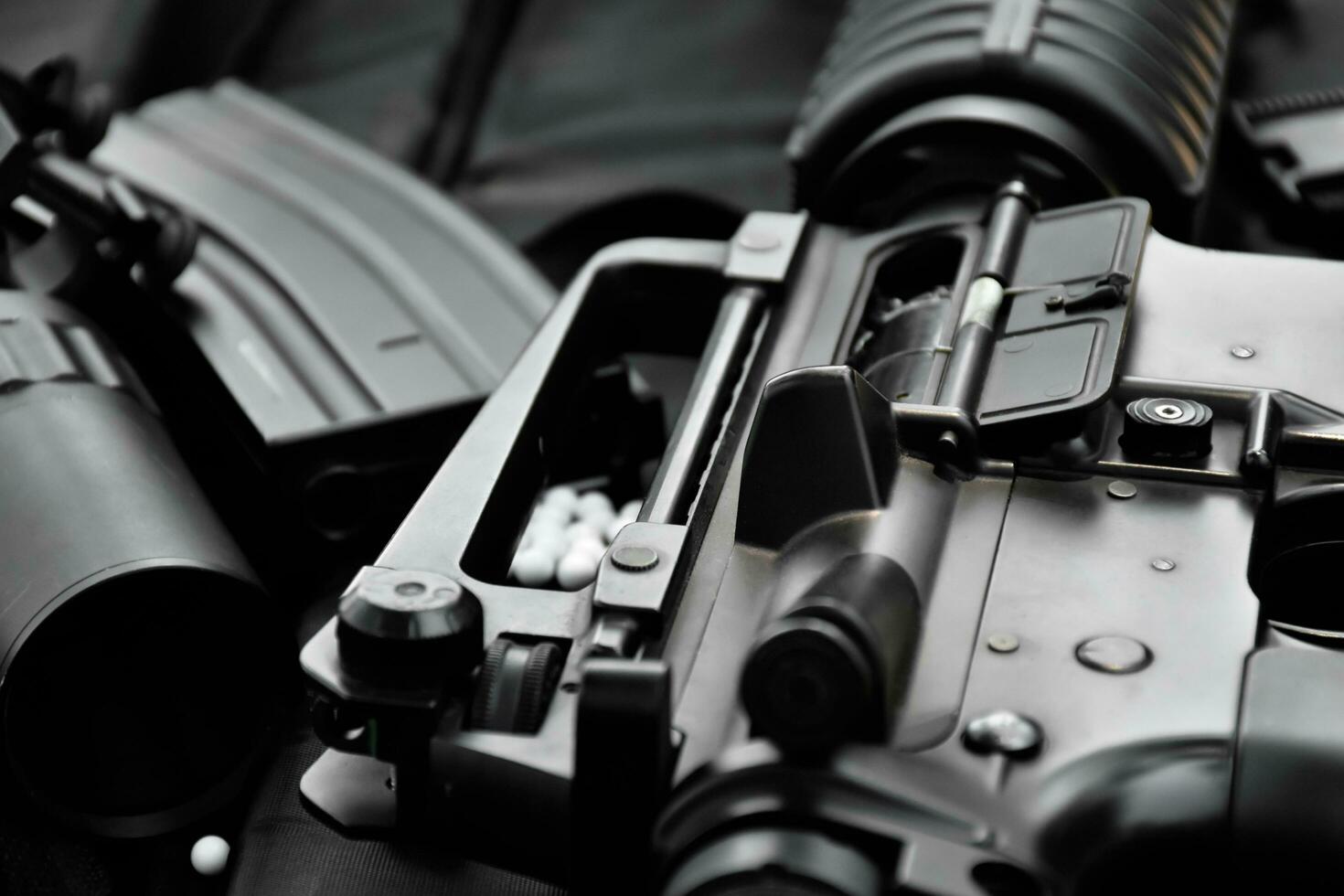 Airsoft gun or BB gun equipments, bullets, gun body, and binocular on dark leather floor background, soft and selective focus. shooting sports and recreational activity concept. photo