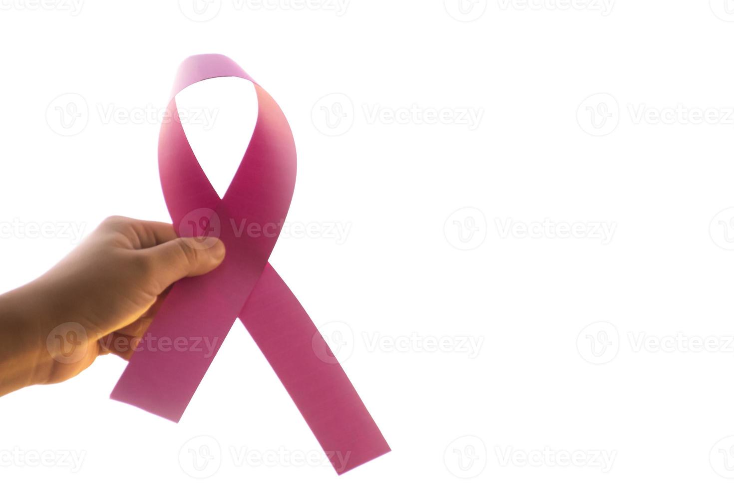 Pink paper ribbon holding in hands of female teenager to show and to call out all people around the world to support and to attend the breast cancer campaign of woman, soft and selective focus. photo