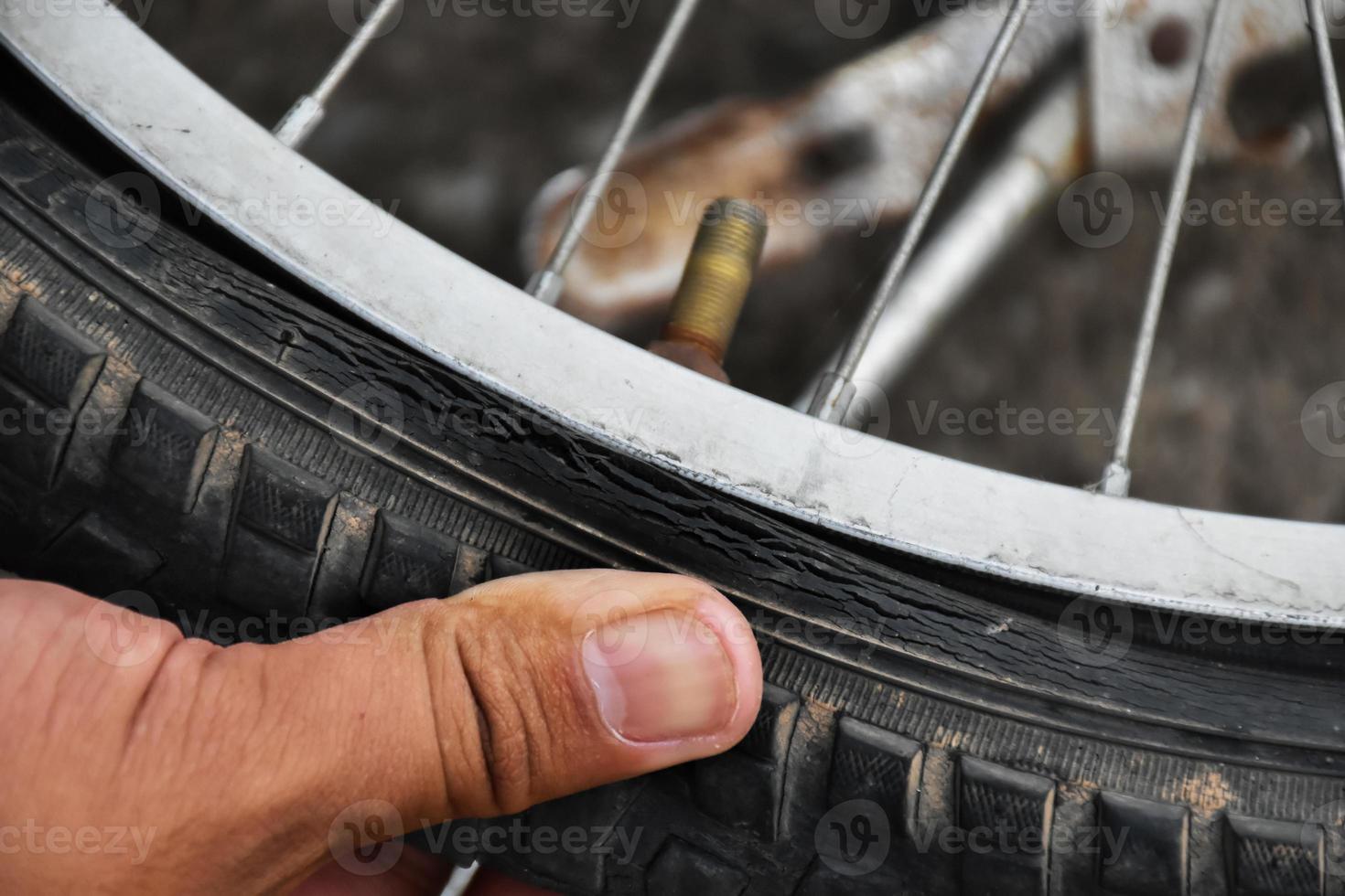 Bike tire was flat and parked on the pavement, the repairman is checking it. Soft and selective focus on tire. photo