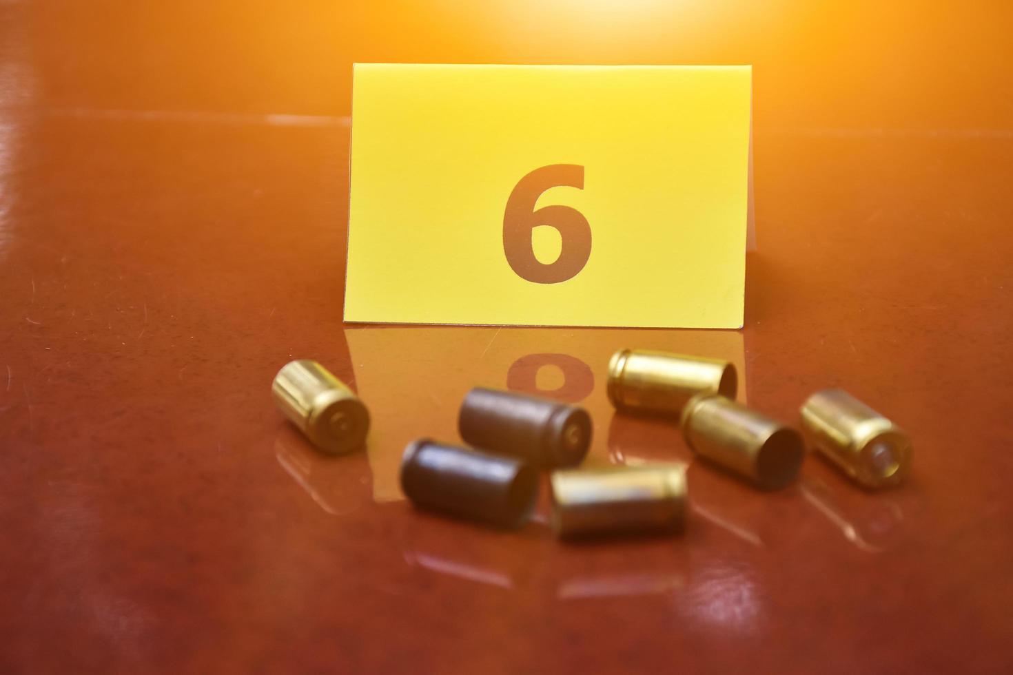 Pistol's bullet shells and yellow number paper sign on floor, concept for keeping physical evidences of the use of pistols, guns and bullet shells at the point of the murder. photo