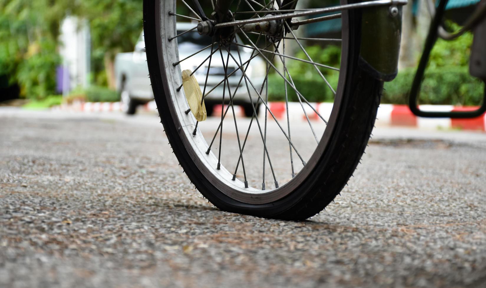 Closeup flat rear wheel of the bike which parked on pavement, soft and selective focus. photo