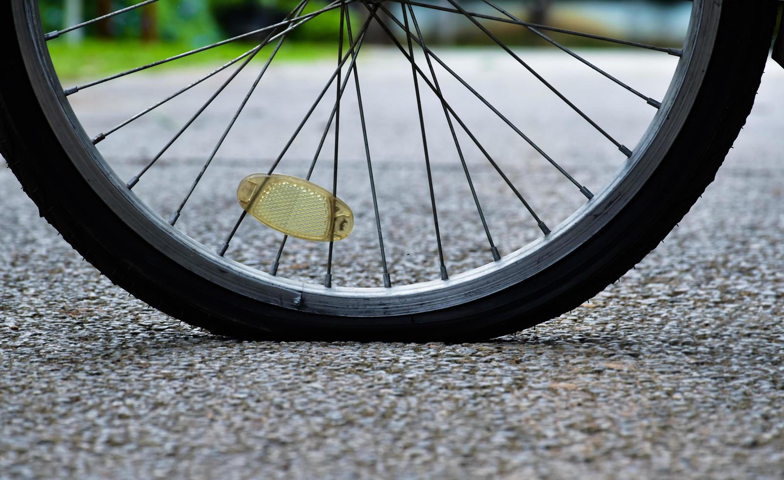 Closeup flat rear wheel of the bike which parked on pavement, soft and selective focus. photo