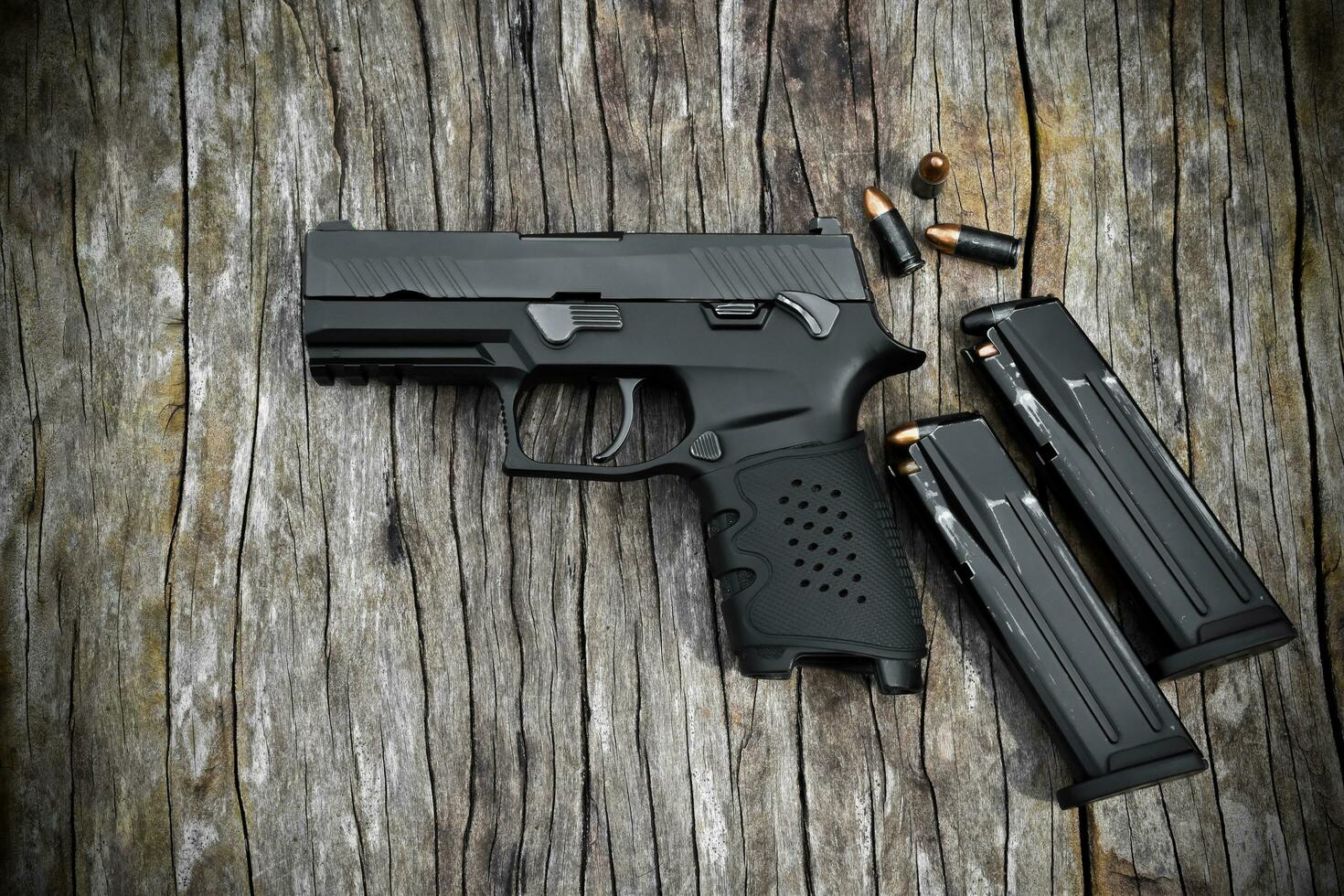 Automatic black 9mm pistol and bullets on black leather background, selective and soft focus. photo