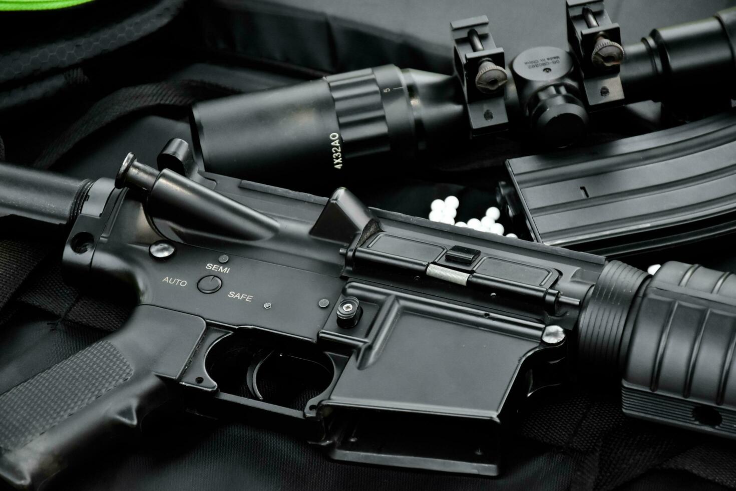 Airsoft gun or BB gun equipments, bullets, gun body, and binocular on dark leather floor background, soft and selective focus. shooting sports and recreational activity concept. photo