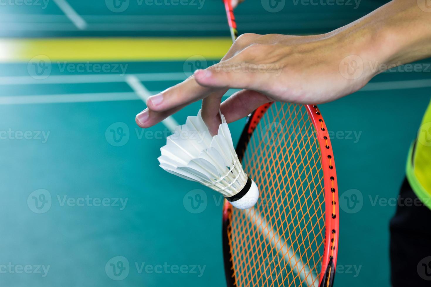 Badminton player holds racket and white cream shuttlecock in front of the net before serving it to another side of the court. photo