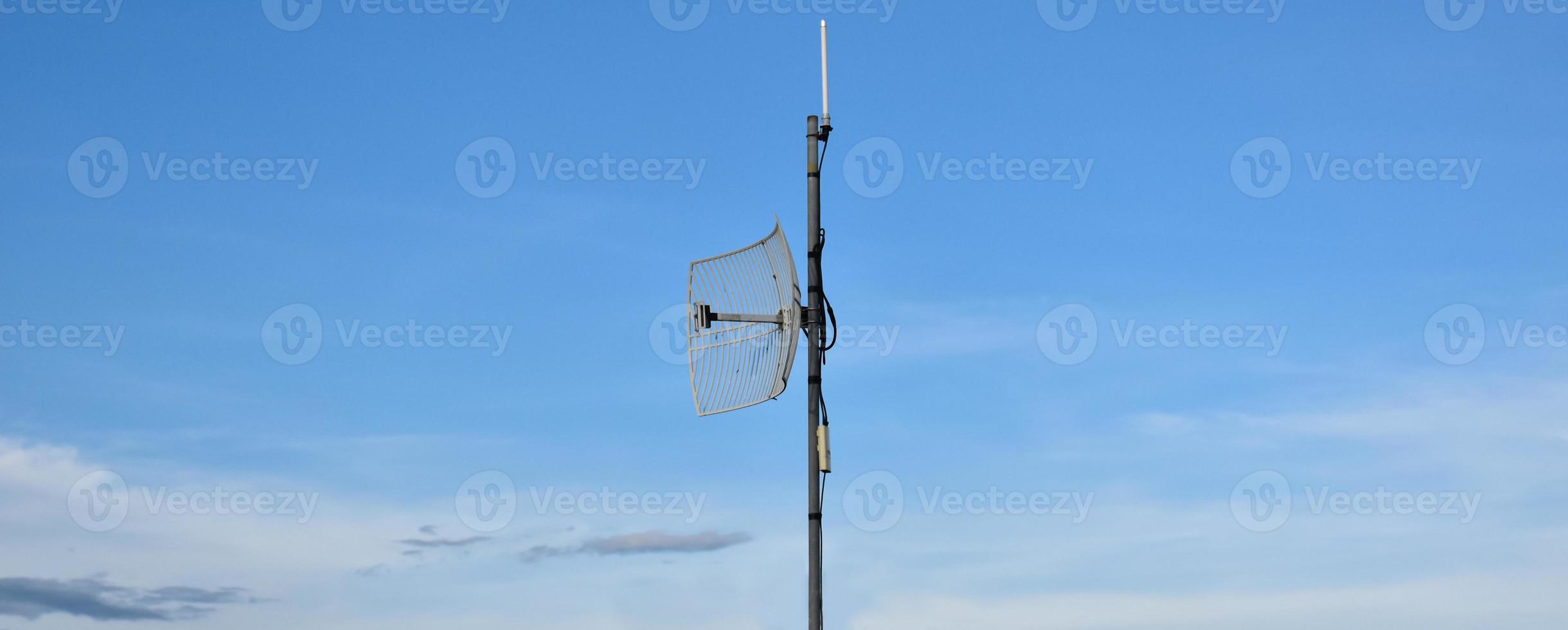 receptor wifi de Internet al aire libre y antena repetidora en el techo del edificio con un fondo azul claro. foto