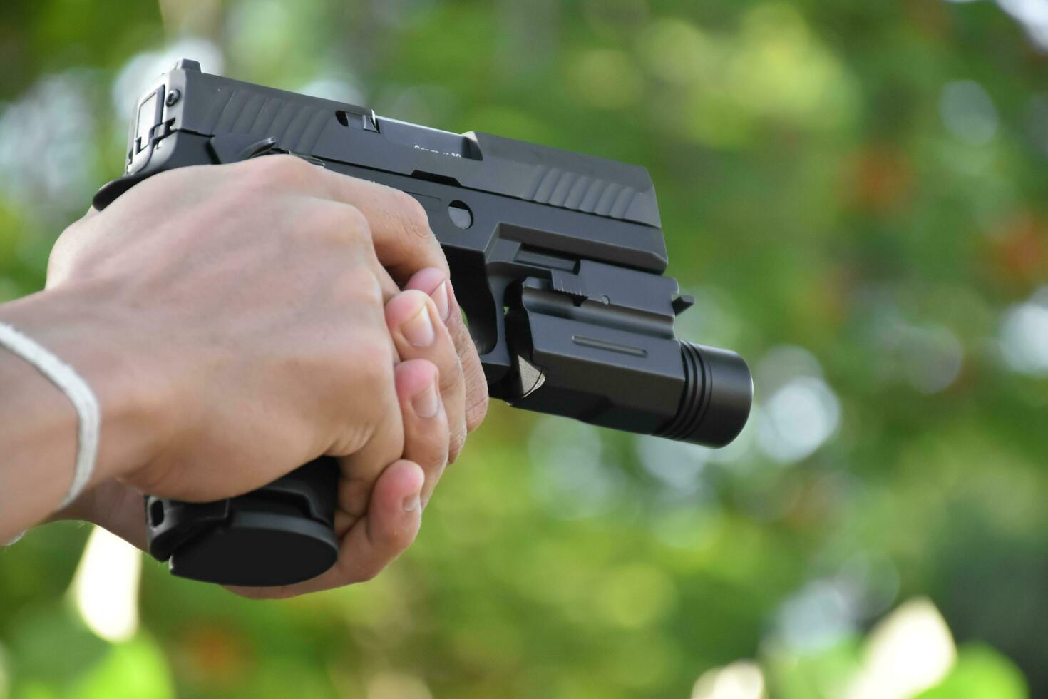 Pistol holding in hands of gunman at the shooting club, soft and selective focus on pistol, concept for shooting sport, bodyguard, security training, mafias, gangsters and self protections. photo