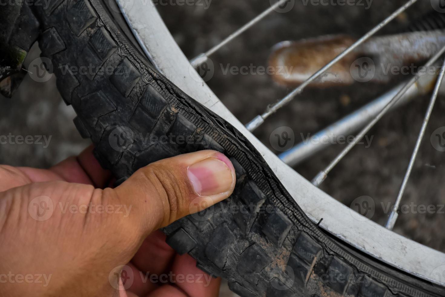 Bike tire was flat and parked on the pavement, the repairman is checking it. Soft and selective focus on tire. photo