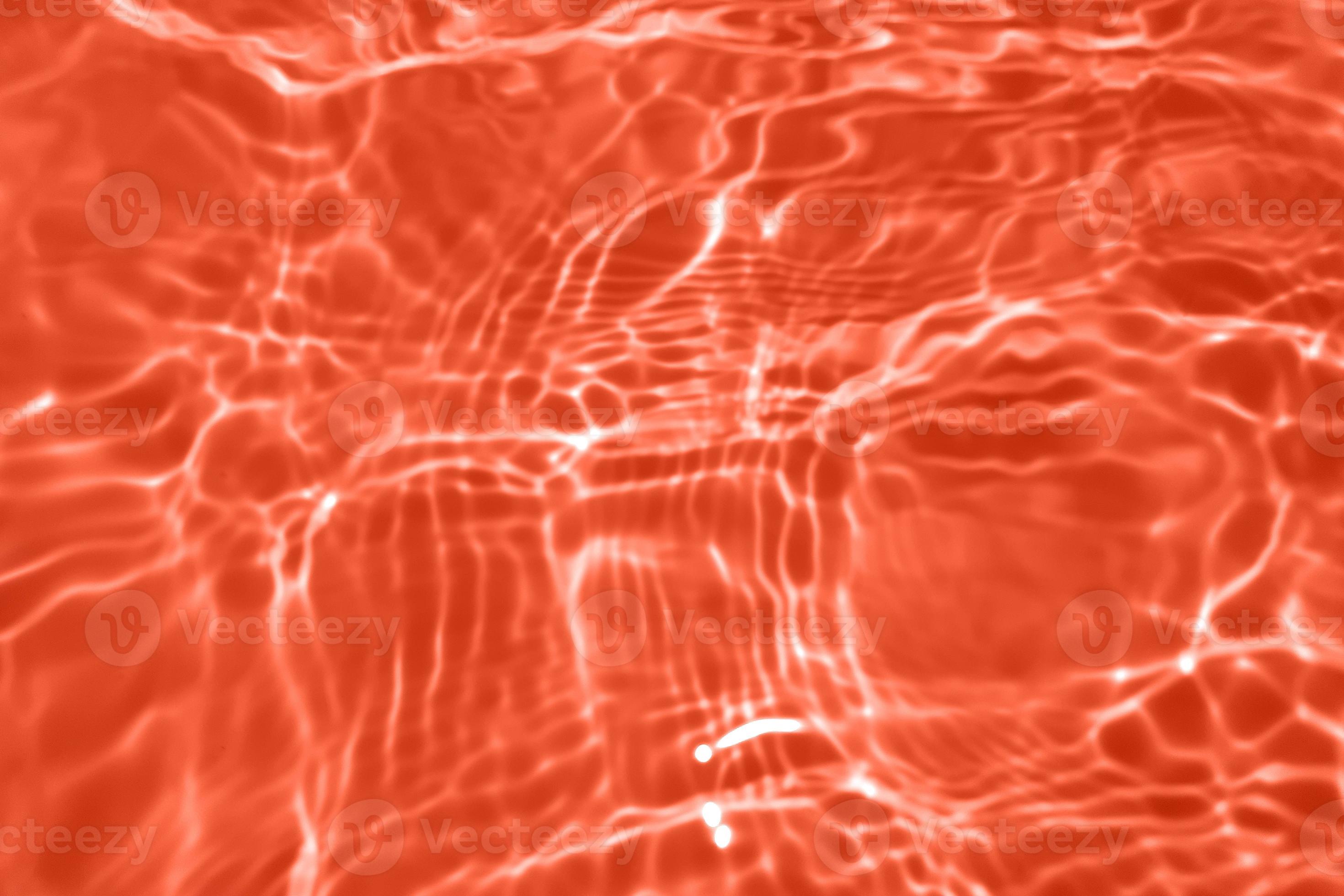 Defocus blurred transparent orange colored clear calm water surface