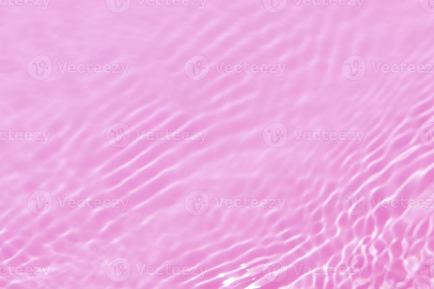 Defocus blurred transparent pink colored clear calm water surface texture with splash, bubble. Shining pink water ripple background. Surface of water in swimming pool. Tropical pink water color flow. photo