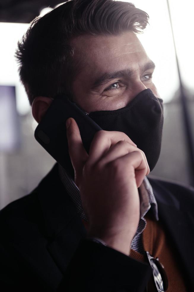 business man wearing coronavirus  medical face mask while using smartphone photo