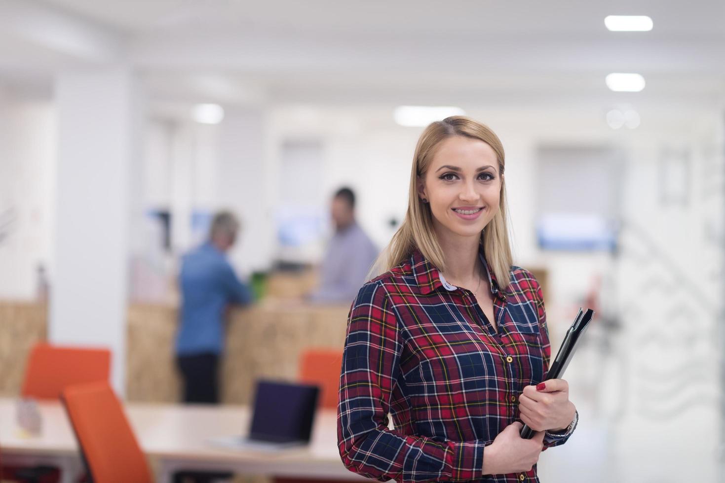 retrato, de, joven, mujer de negocios, en, oficina, con, equipo, en, plano de fondo foto