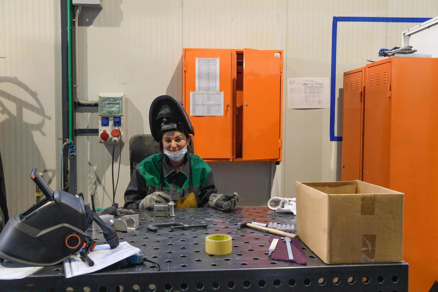 A woman employed in a modern factory for the production and processing of metals in a work uniform welds metal materials photo