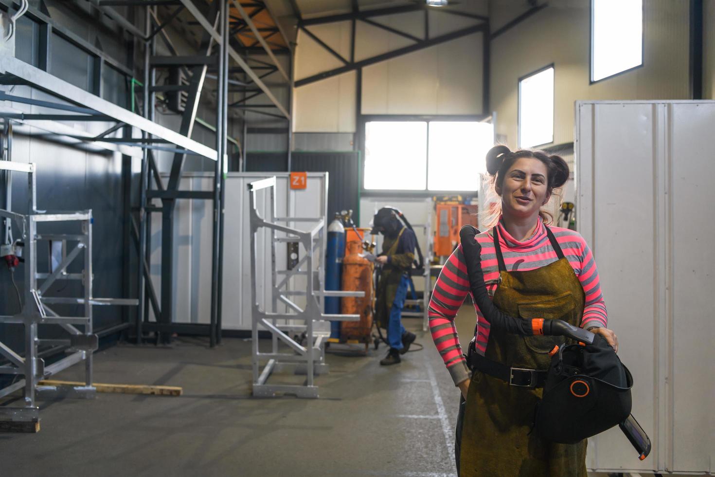 un retrato de una mujer soldadora sosteniendo un casco y preparándose para un día de trabajo en la industria del metal foto