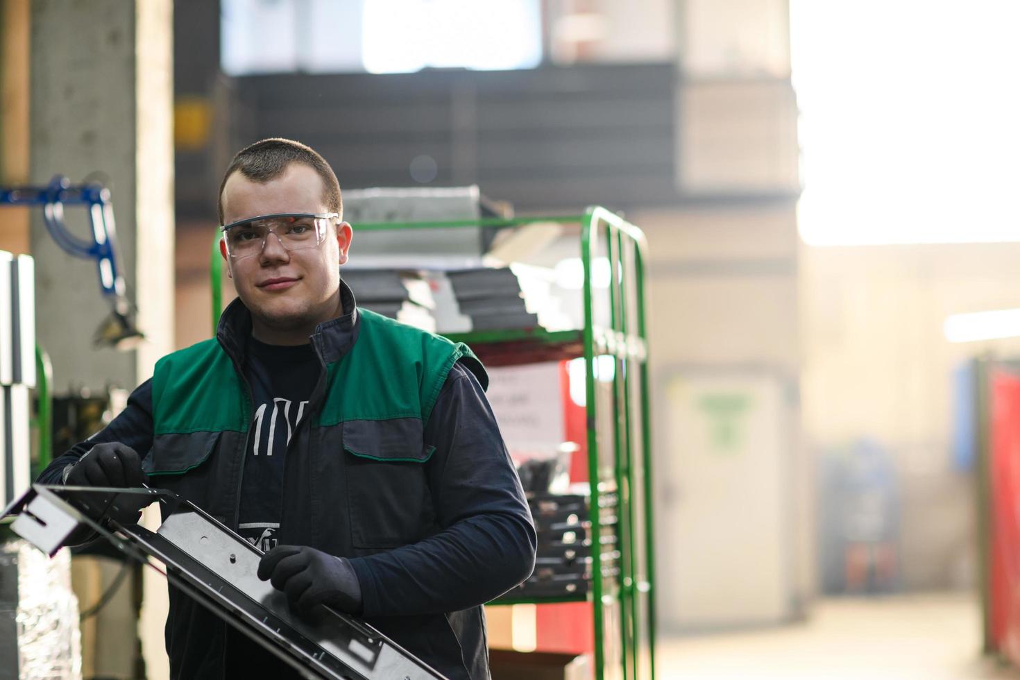 a uniformed worker working in a modern metal production and processing factory assembles parts of a new machine on his desk photo