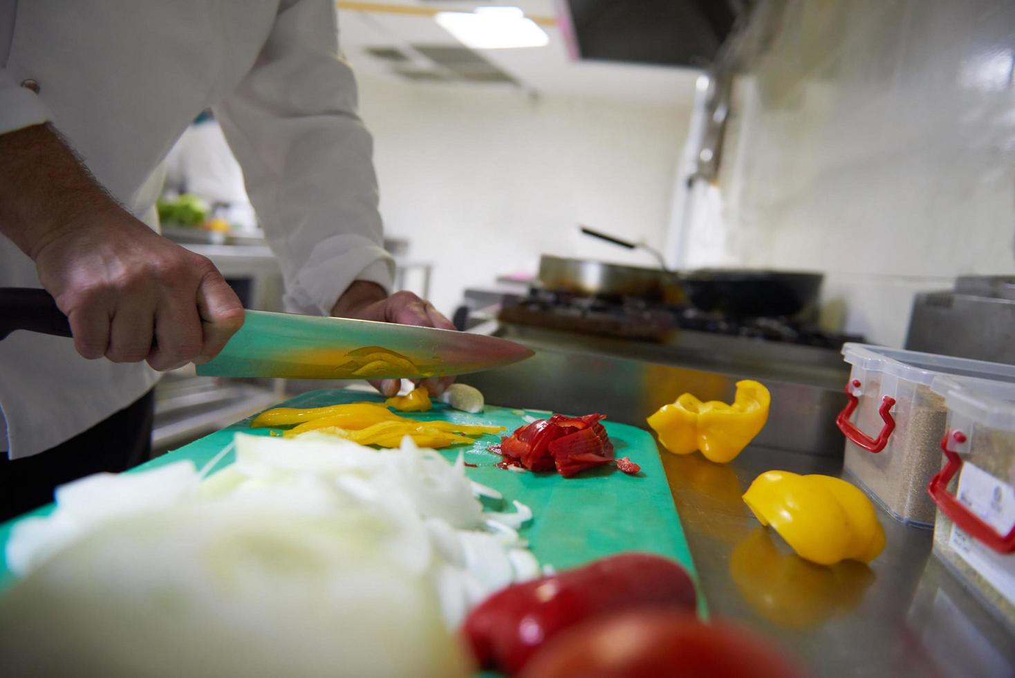 chef in hotel kitchen  slice  vegetables with knife photo