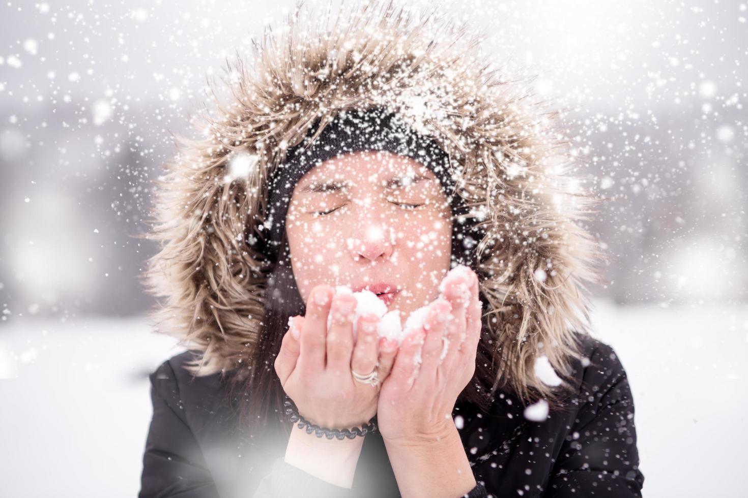 young woman blowing snow on snowy day photo