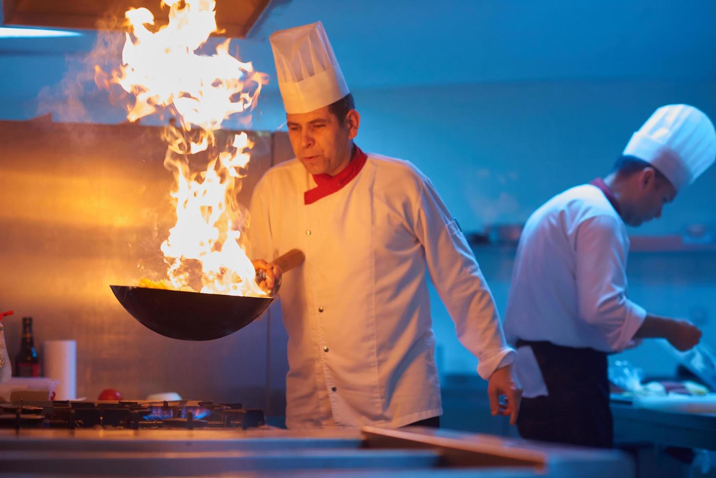 chef in hotel kitchen prepare food with fire photo