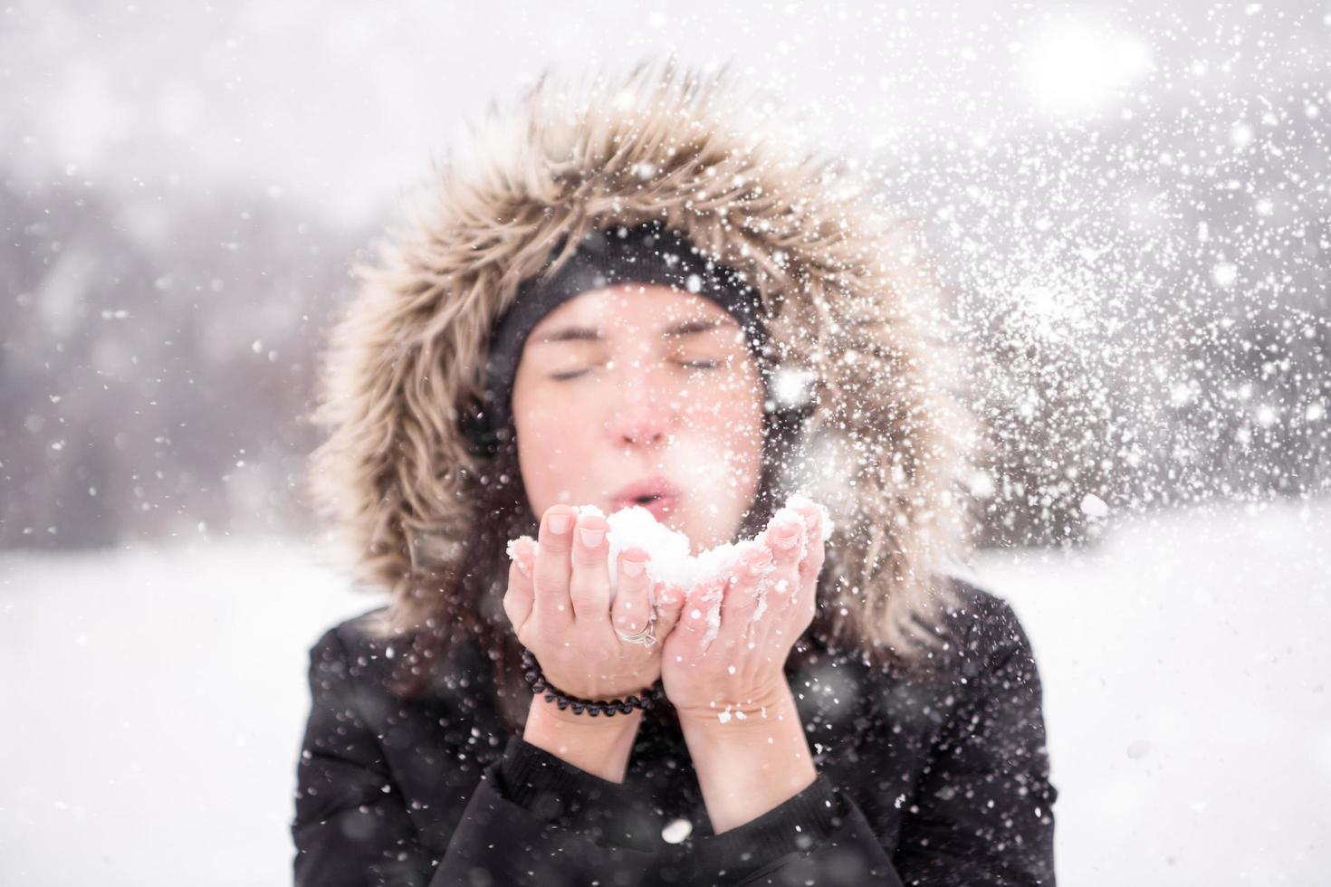 young woman blowing snow on snowy day photo