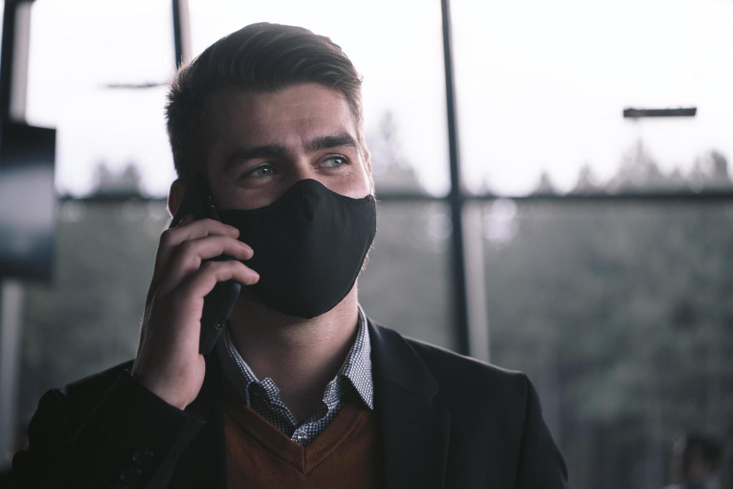 business man wearing coronavirus  medical face mask while using smartphone photo