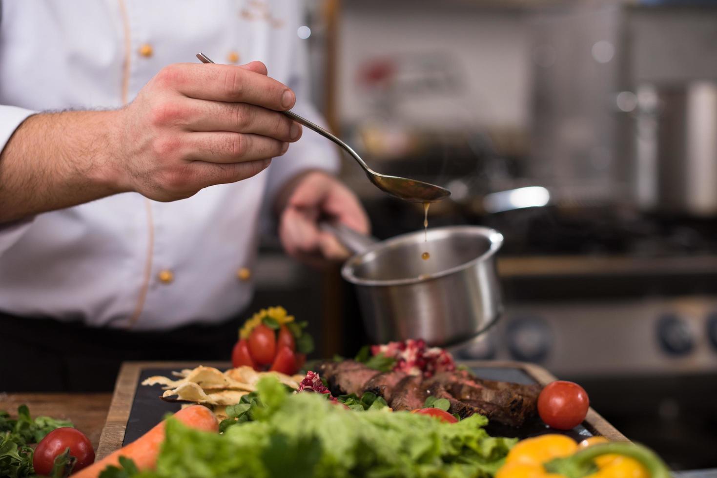 Chef hand finishing steak meat plate photo