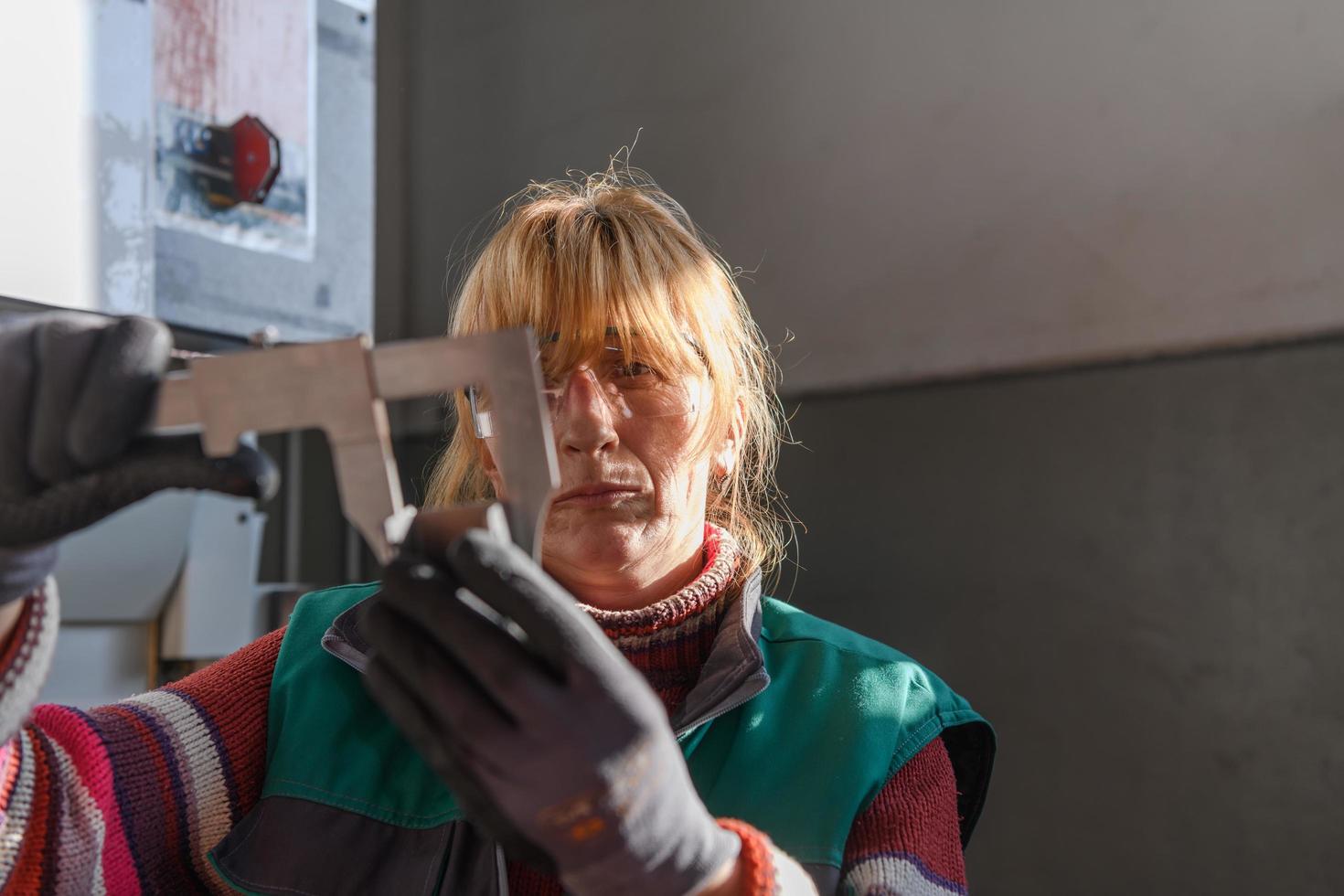 una mujer que trabaja en una fábrica moderna para la producción y procesamiento de metales, preparando y midiendo materiales que van al procesamiento de máquinas cnc foto