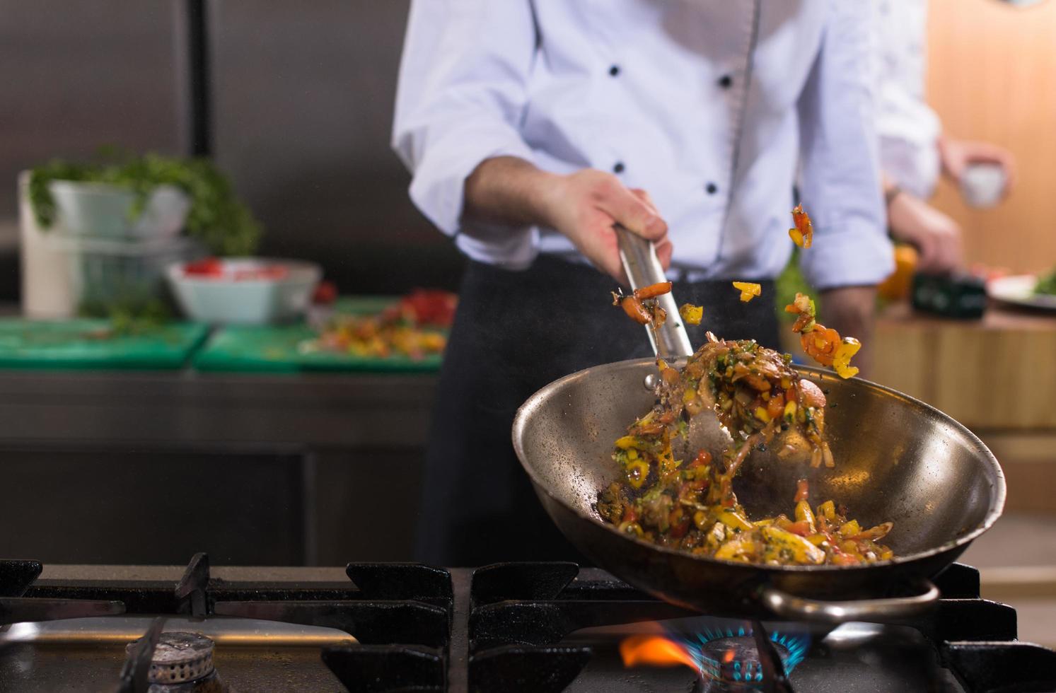 chef flipping vegetables in wok photo