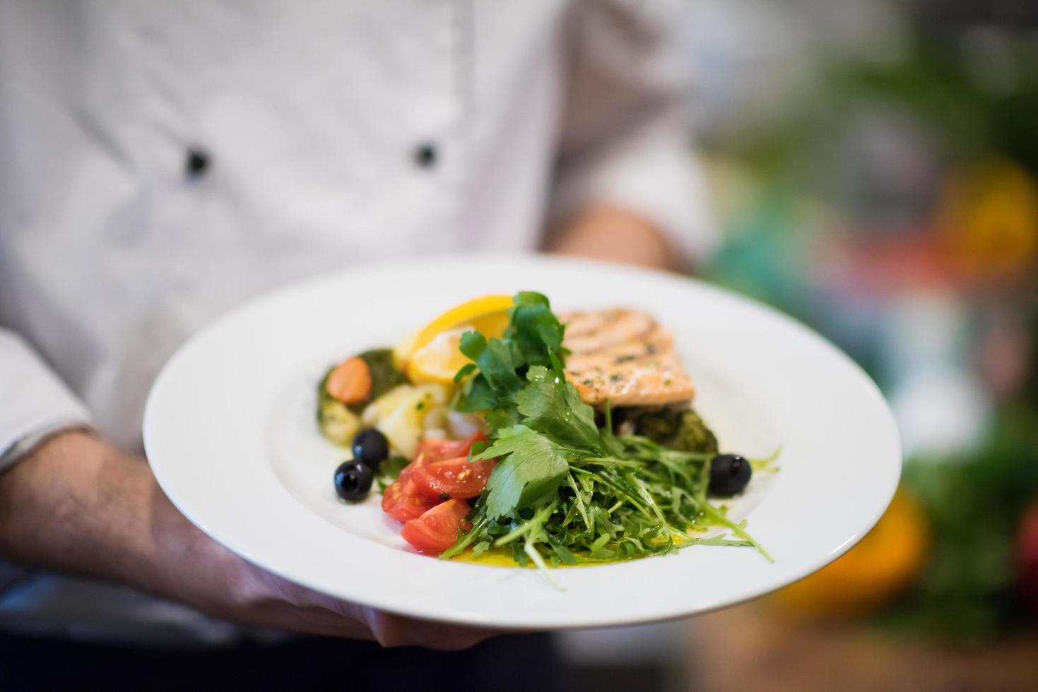 Chef hands holding dish of fried Salmon fish fillet photo