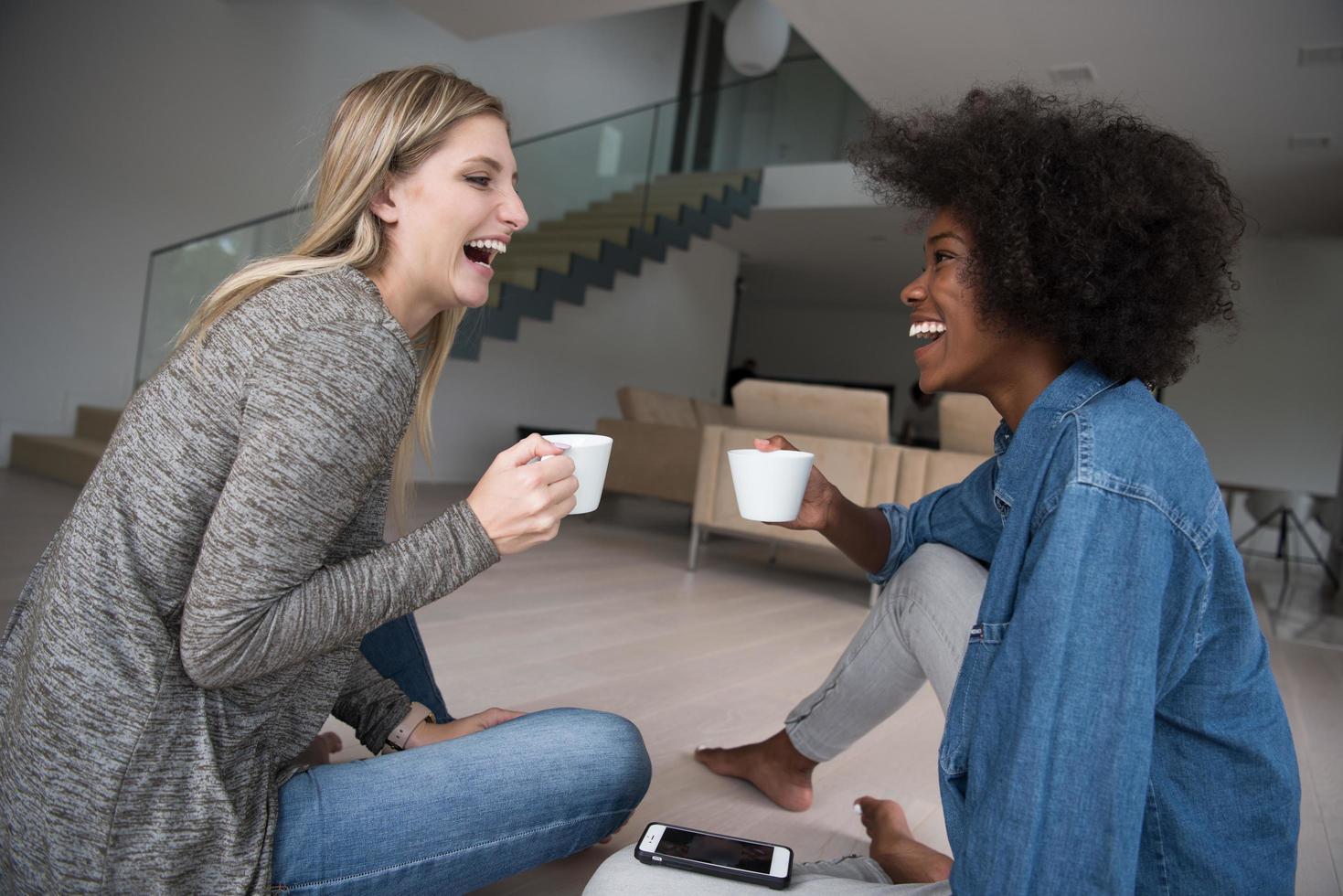 young multiethnic women sit on the floor and drinking coffee photo