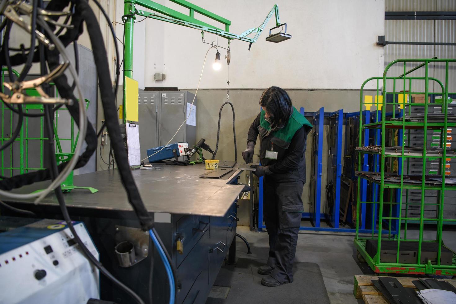 a woman working in the modern metal production and processing industry welding the product and prepares it for a cnc machine photo