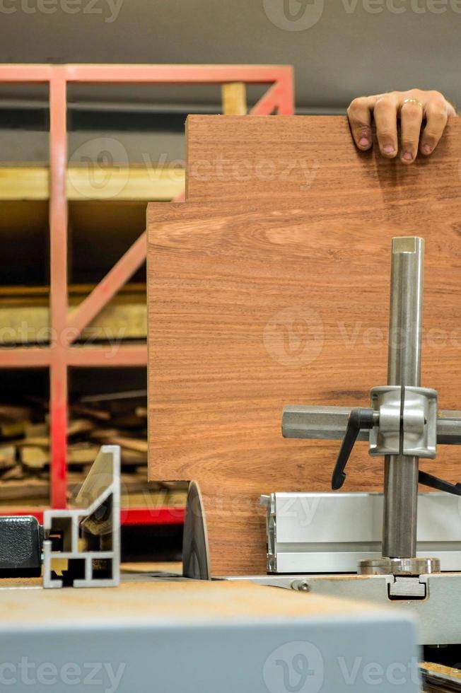 A man cuts wood on a circular saw in a joinery, band saw, holding a plank photo