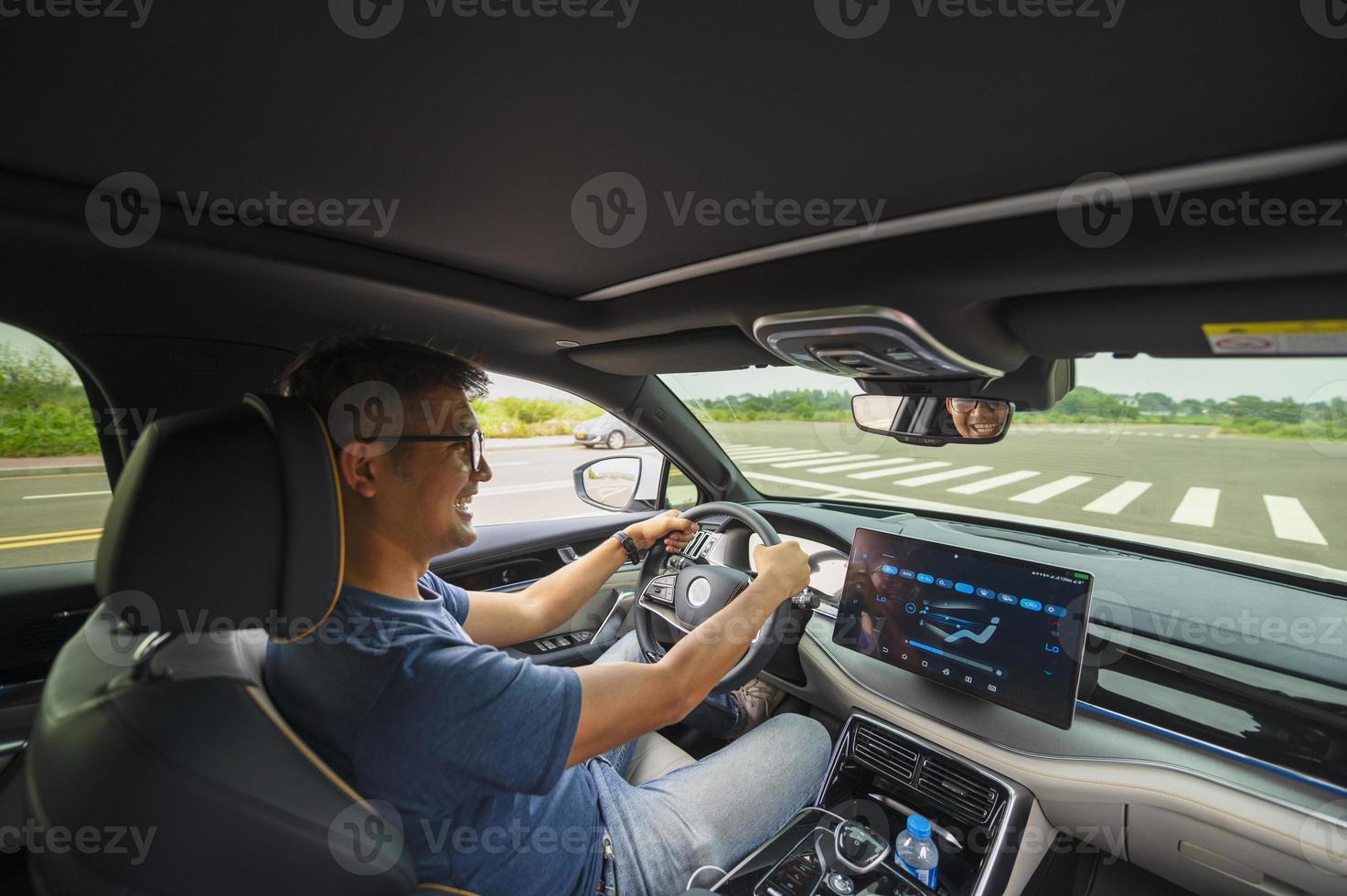 An Asian man drives from town to go on a summer vacation. Happy Asian man in casual wear and beautiful new driving glasses. photo