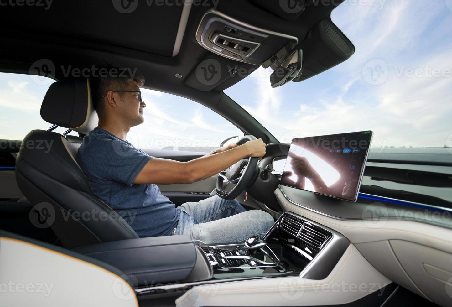 An Asian man drives from town to go on a summer vacation. Happy Asian man in casual wear and beautiful new driving glasses. photo