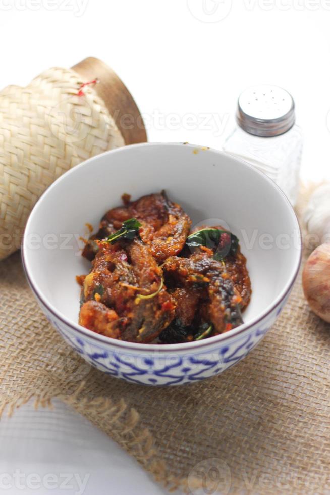 Spicy Stir Fried Catfish served in a Thai style patterned bowl on a white table. photo