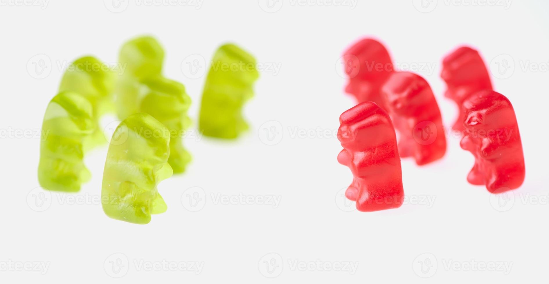 green gummy bears on the left and red gummy bears on the right side on white background photo