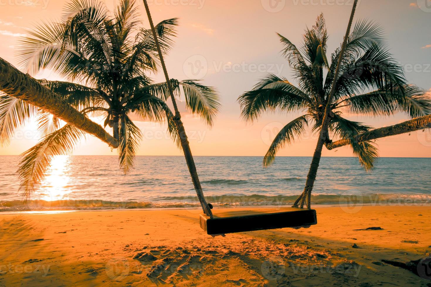 Wood swing beautiful sunset on the sea beach with palm tree and blue sky for travel in holiday relax time, photo style vintage