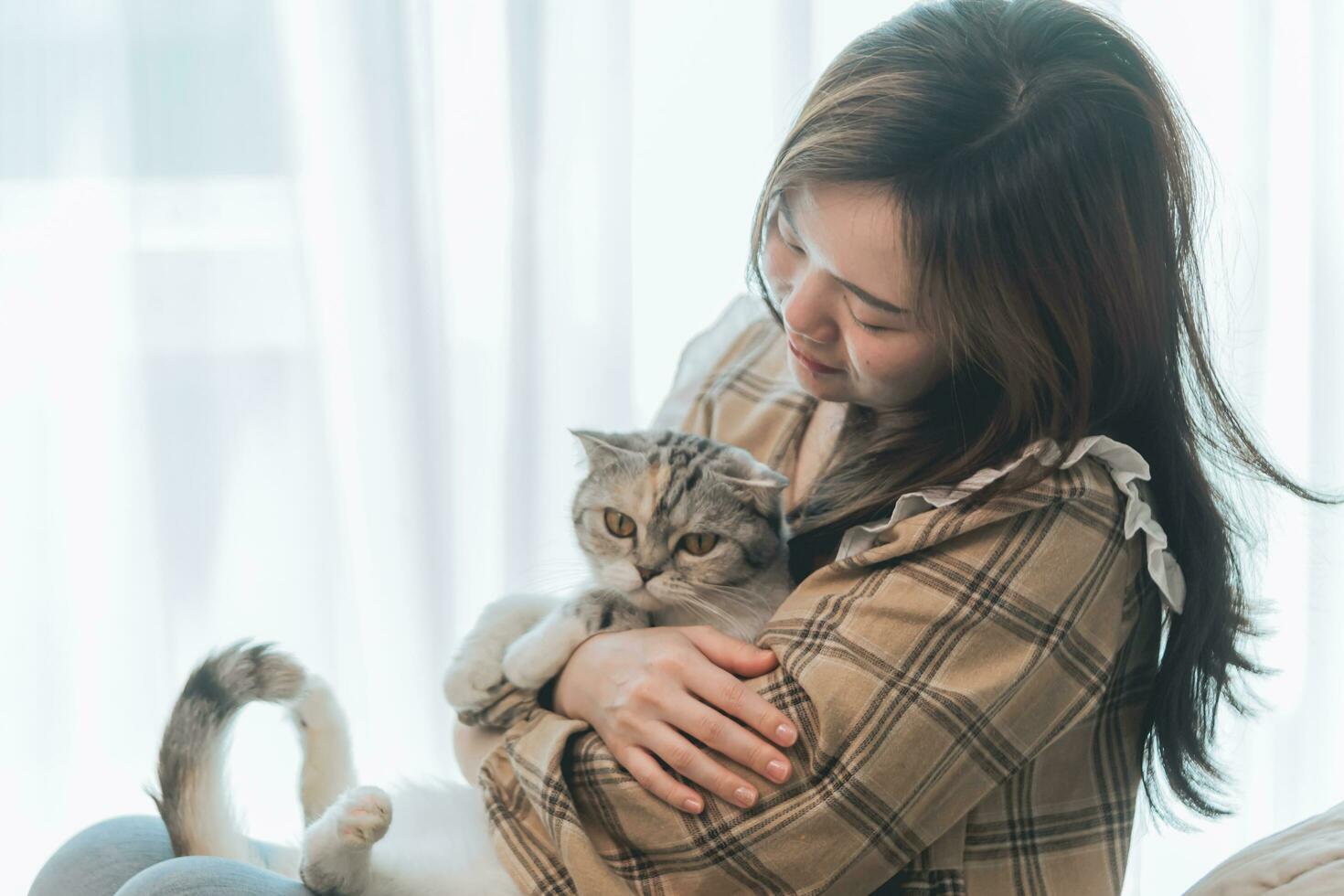 Portrait of young woman holding cute cat. Female hugging her cute long hair kitty. Background, copy space, close up. Adorable domestic pet concept. photo