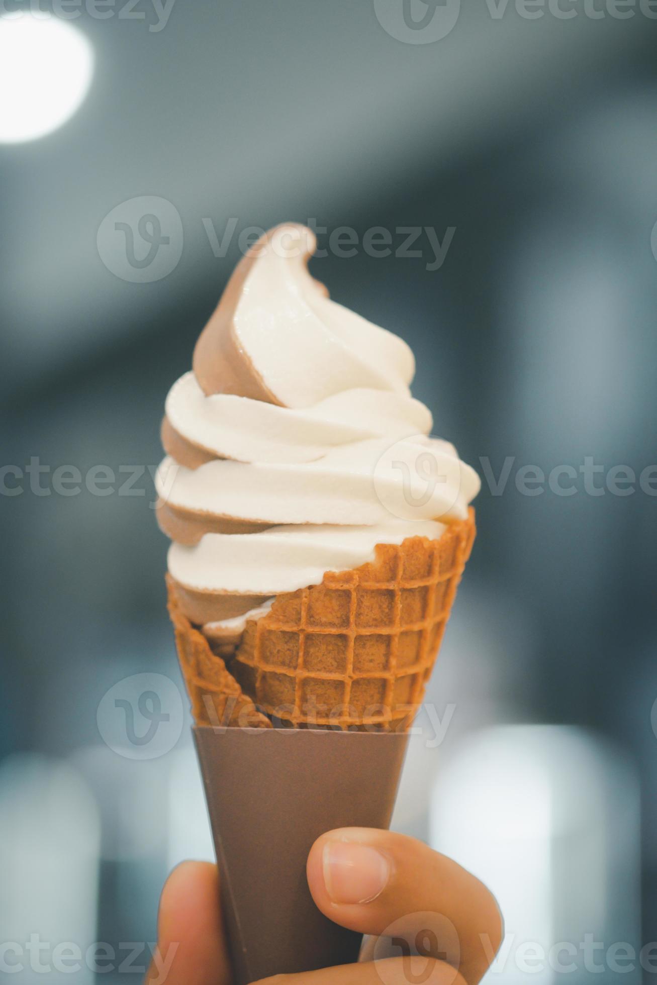 Twotone soft serve ice cream cone in hand 12168567 Stock Photo at Vecteezy