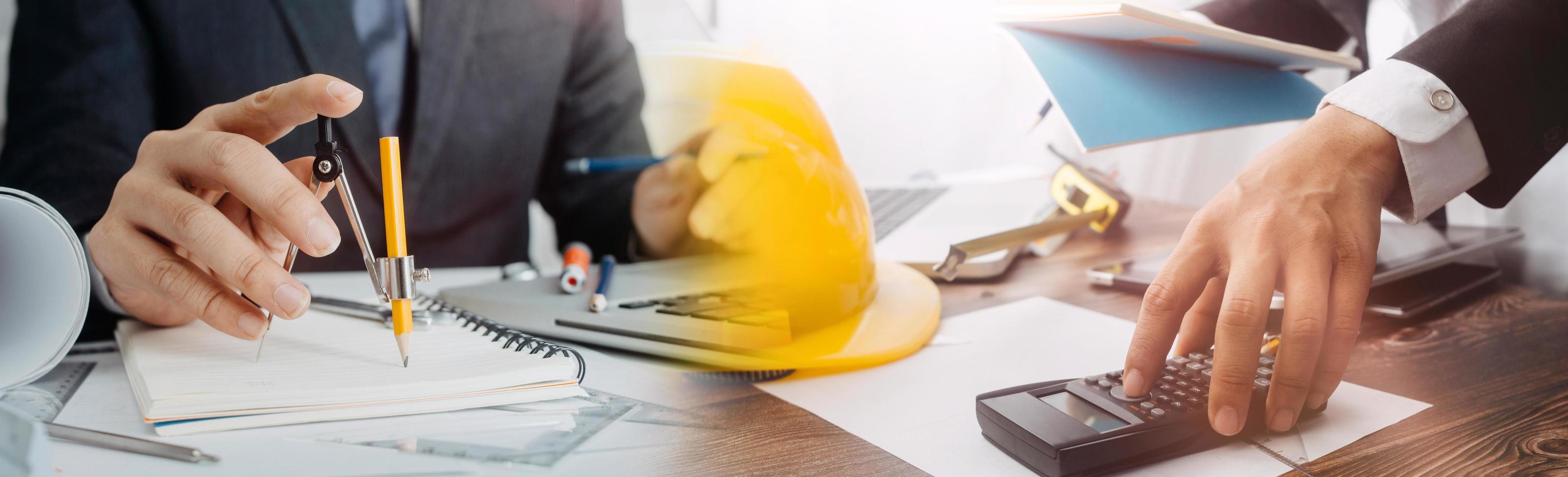 Two colleagues discussing data working and tablet, laptop with on on architectural project at construction site at desk in office photo