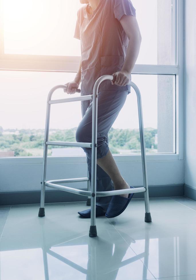 young asian physical therapist working with senior woman on walking with a walker photo