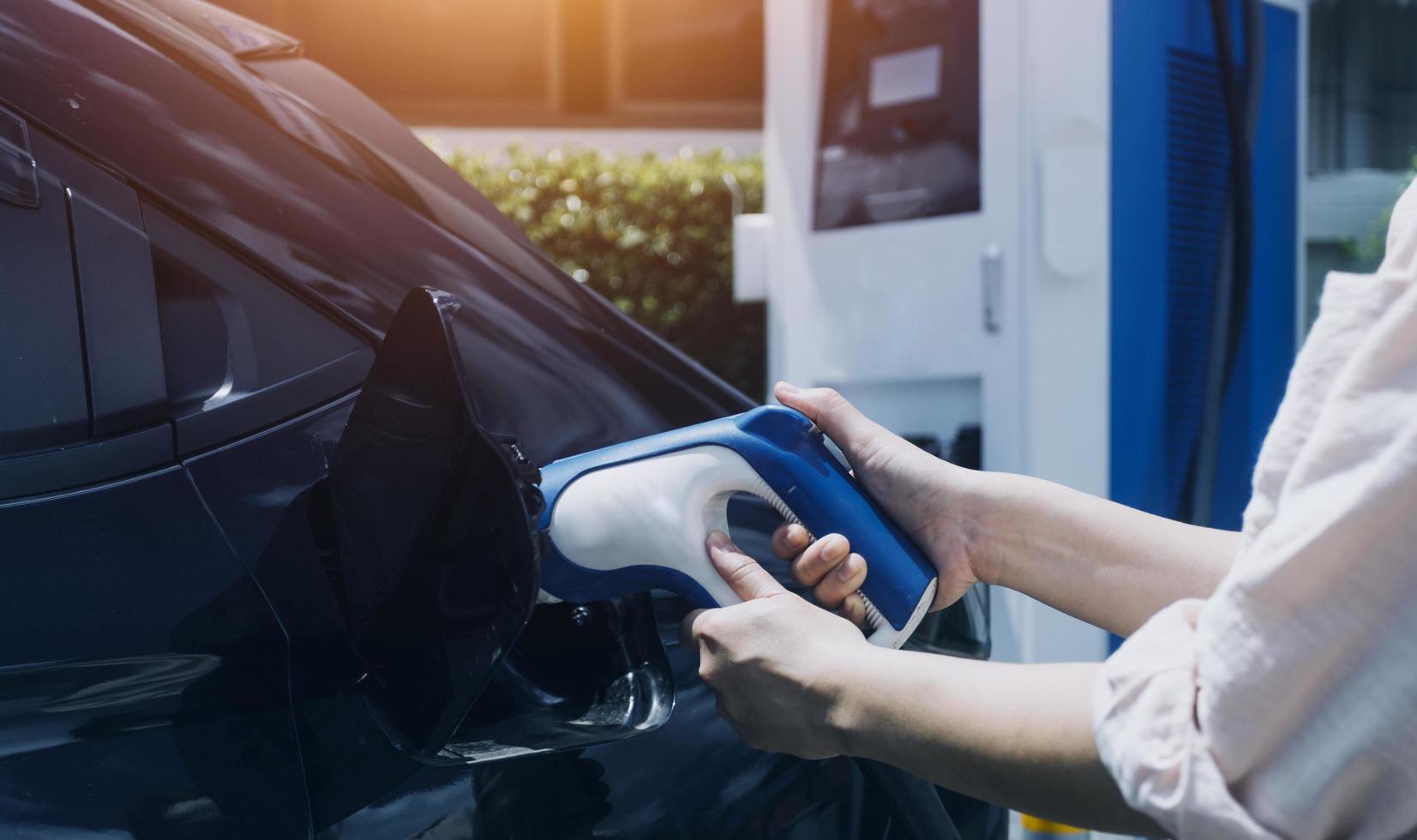 Hand plugging in a charger in an electric car socket.Electric car or ev is charging at station photo