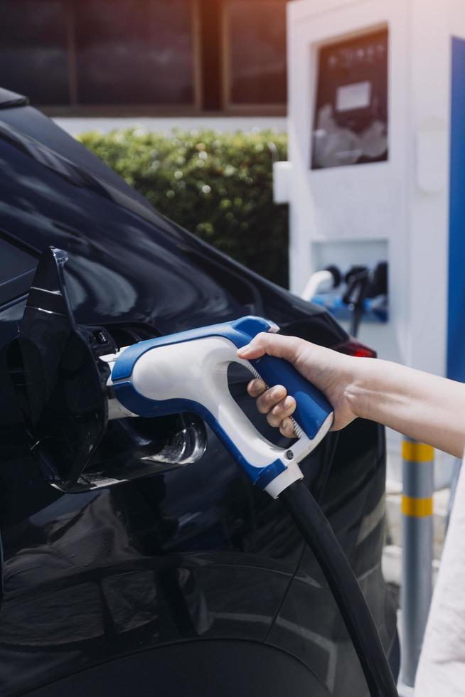 Hand plugging in a charger in an electric car socket.Electric car or ev is charging at station photo