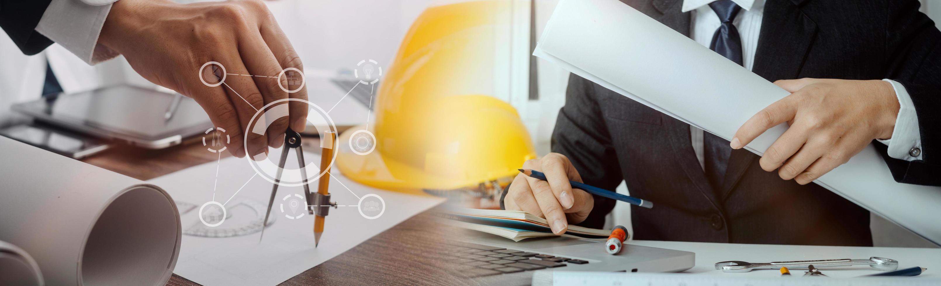 Two colleagues discussing data working and tablet, laptop with on on architectural project at construction site at desk in office photo