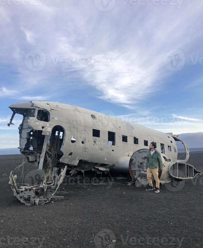 hombre frente a un accidente de avión abandonado en solheimasandur, islandia, en la noche con un cielo dramático en el fondo foto