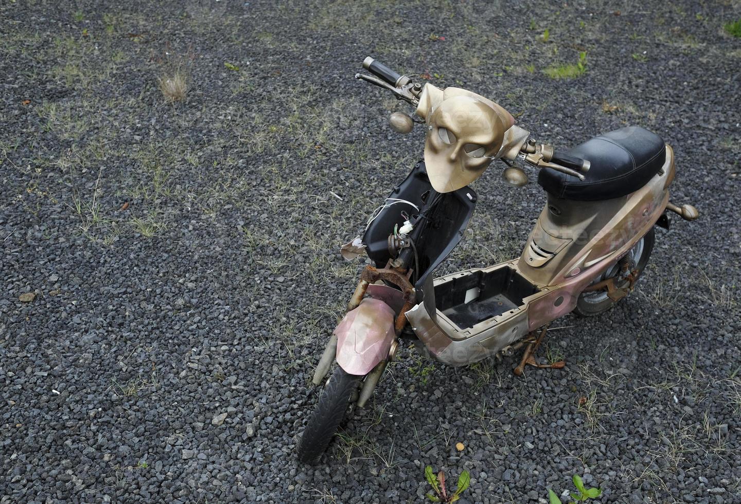 Abandoned moped with a golden mask photo