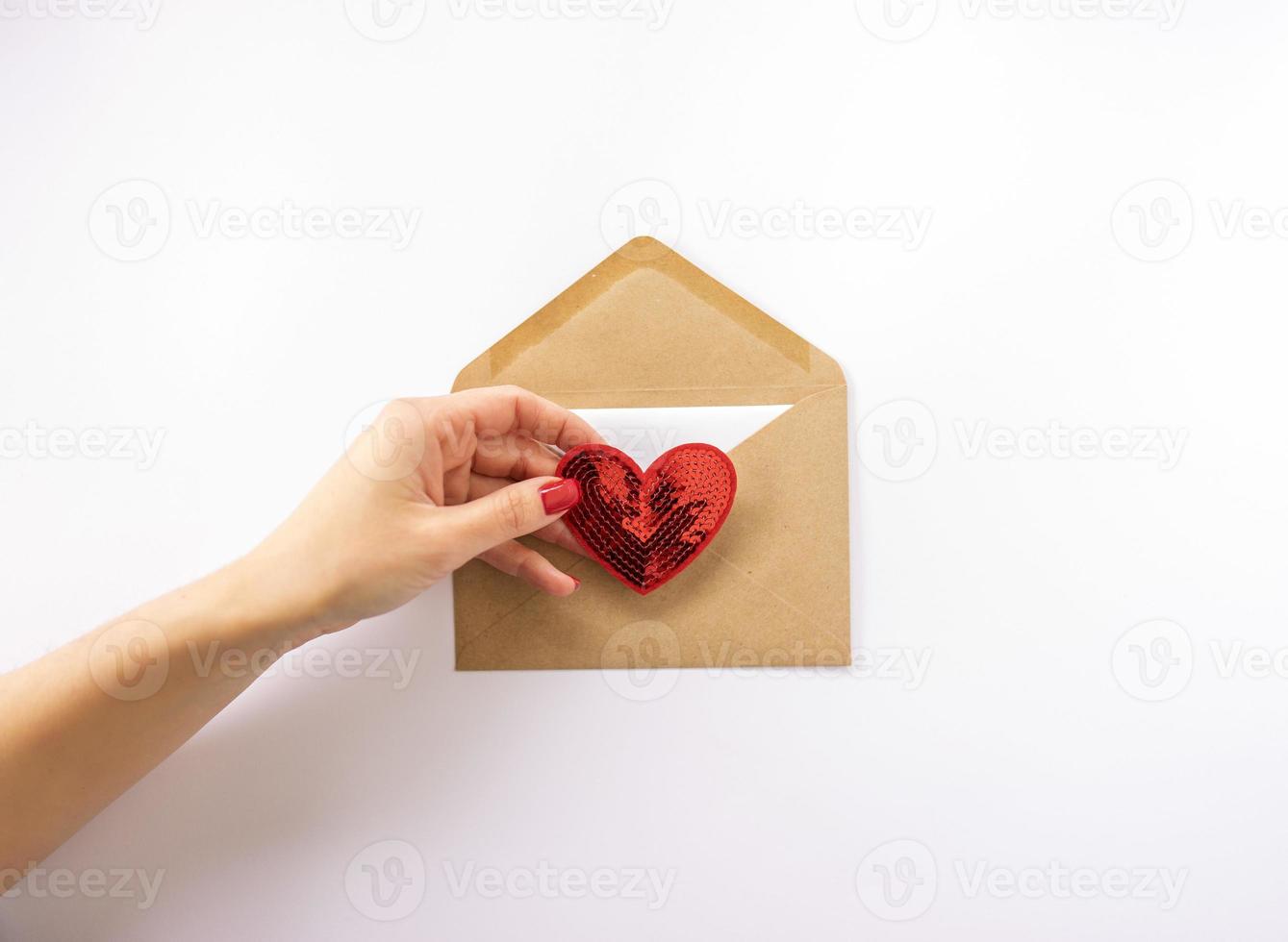 A woman holding a red heart in her hand and sending in in an envelope for Valentines Day photo