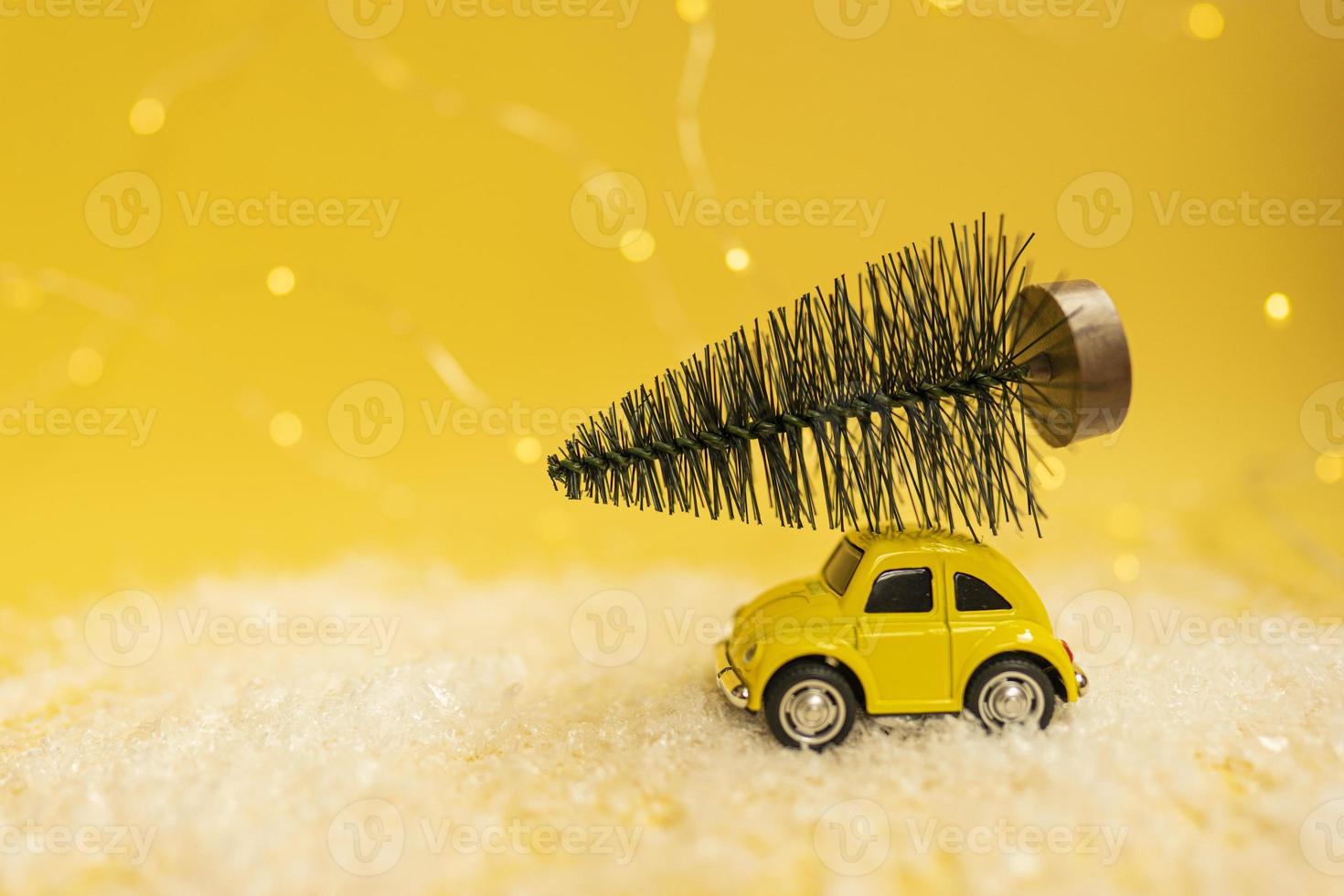 un mini camión amarillo con un arco y un árbol de piel verde en la parte superior de pie sobre una nieve foto