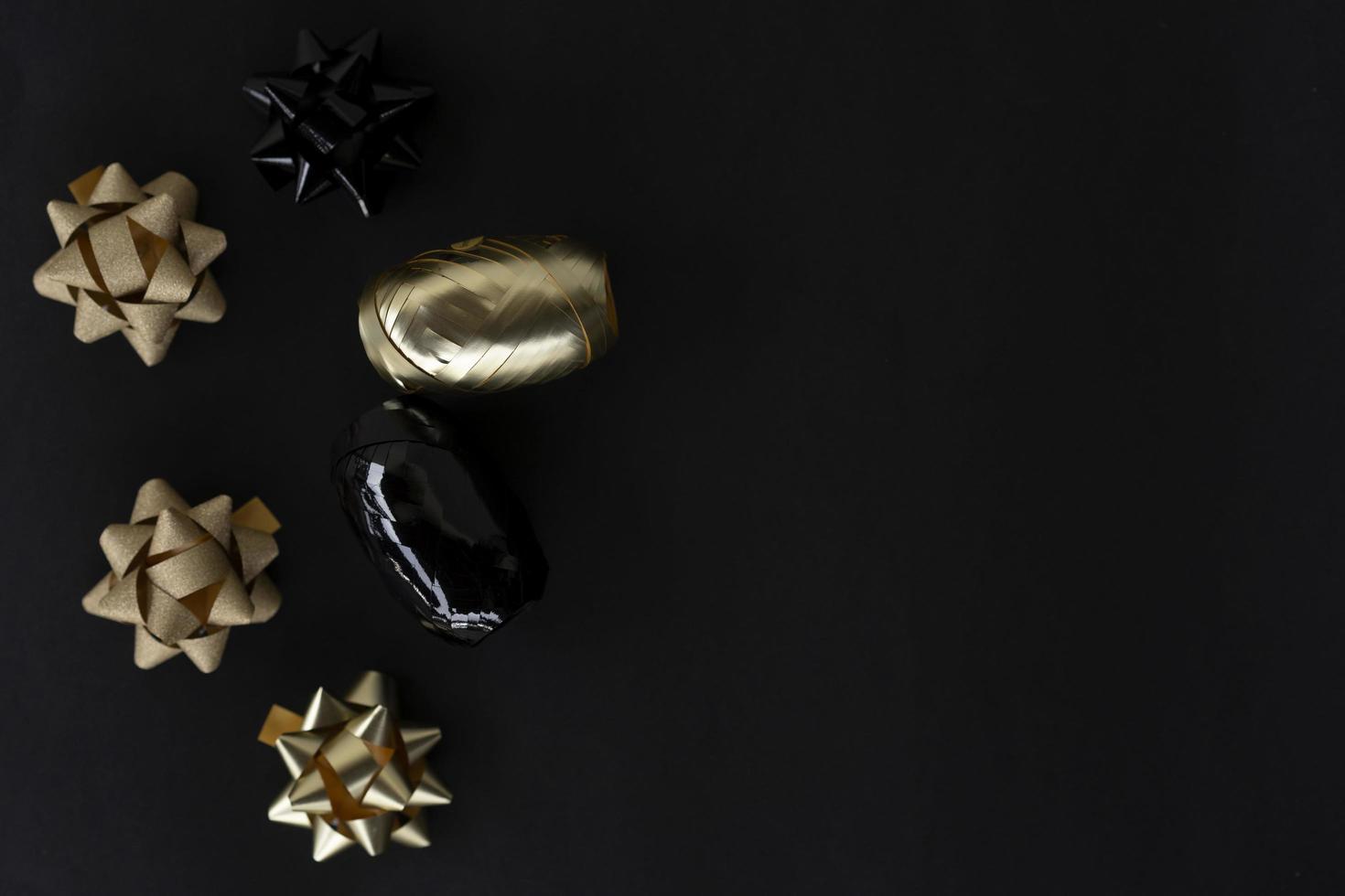 Festive flat lay with golden and black bows lying on a black background photo