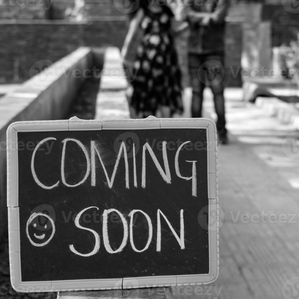 Indian couple posing for maternity baby shoot. The couple is posing in a lawn with green grass and the woman is falunting her baby bump in Lodhi Garden in New Delhi, India - Black and White photo